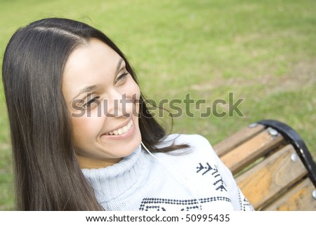 Beautiful girl in a park listening to music from your mobile phone