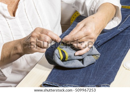 person working,seamstress woman sews the bottoms of the pants Royalty-Free Stock Photo #509967253