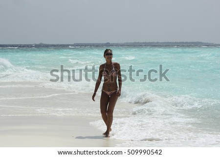 smiling woman in in a colored bikini walking  on beach