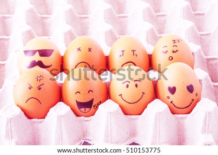 eight brown eggs  with faces drawn  arranged in carton