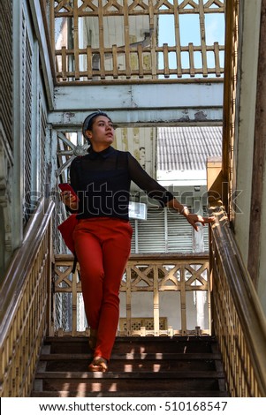 Teenage Asian girl Walking up and down stairs in the old wood building.