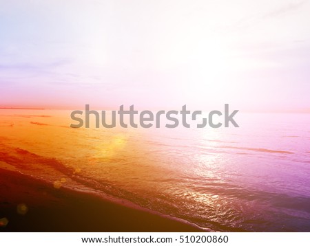 Blurred beach and calm sea waves on sunset background. Vintage landscape blur warm soft relax. Natural colors sun light in summer. Abstract bokeh flare virtual sunrise in tropic horizon beautiful.