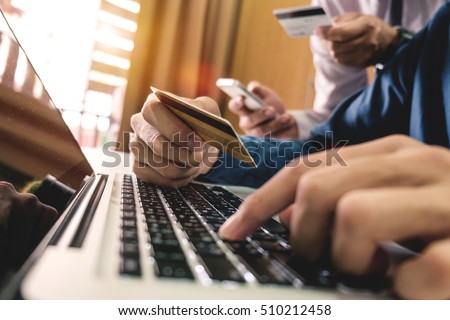 business hands using laptop,tablet and holding credit card with social media as Online shopping concept and two colleagues discussing data in morning light