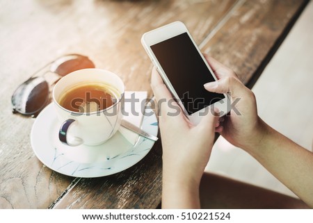 girl using smart phone in cafe. hand holding smart phone white screen.
