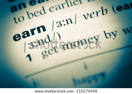 Close up of old English dictionary page with word earn