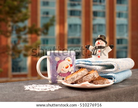 New Year. Tea in a mug with a picture of a snowman and a toy snowman reminded of the new year. Tea and cake for breakfast in the New Year's morning. Tea on the balcony.