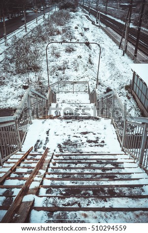 Stairs at railway station and street with cars in winter. Everything is covered with the first snow.