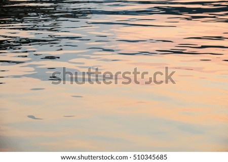 Beautiful water surface reflection wave against golden sunset sky closeup blur texture background