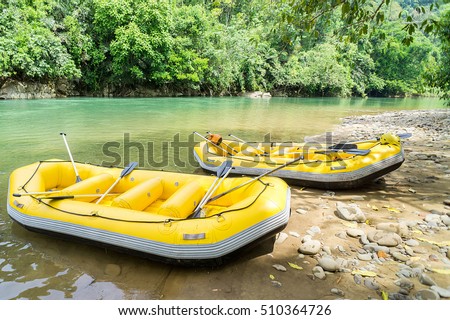 Yellow white water raft static at shaded with shadows under the tree near riverbank of adventure river called Kiulu River in Sabah Malaysian Borneo