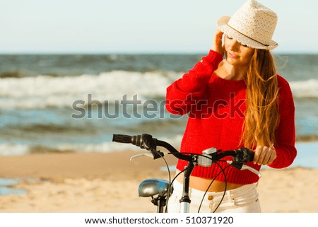 Young active girl with bicycle on seaside. Smiling cute woman resting near to sea in summer. Fashionable tourist on fresh air.