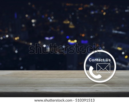 Telephone and mail icon button on wooden table over blur colourful night light city tower background, Contact us concept