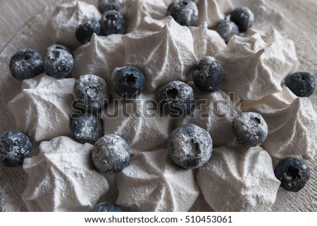 Food picture. Christmas dessert: vanilla meringue with blueberries in powdered sugar at white background