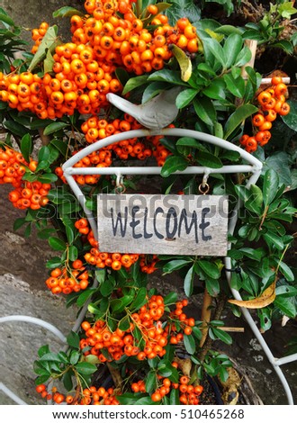 Pyracantha (Firethorn) berries and a Welcome sign in the autumn.