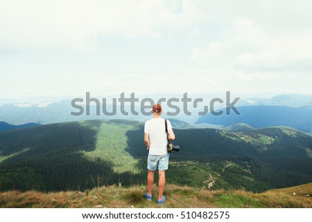 Male photographer standing on top of a mountain with a camera
 