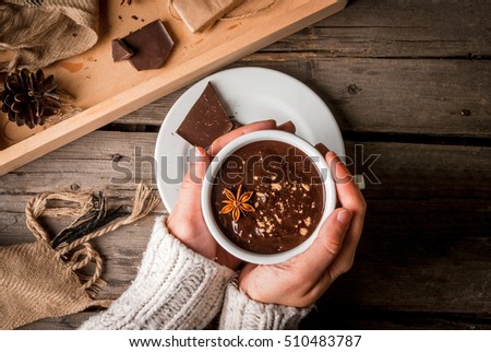 Girl drinks hot chocolate mug, with christmas present on rustic table with blanket or plaid from above, cozy and tasty breakfast or snack. Hands in picture, top view
