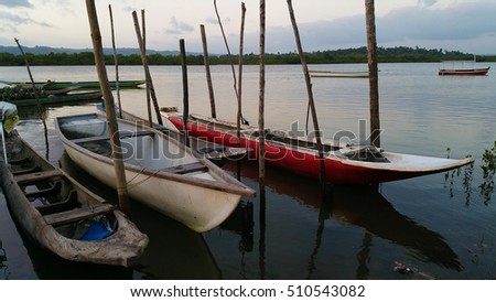 Fishing canoes tied to stakes on the edge of the calm river in l