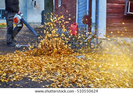 Female worker with leaf blower in the fall. Royalty-Free Stock Photo #510550624