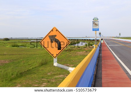 Turn left sign with greenery background and red bicycle lane including bird picture with Thai name and its English name of  Tree Sparrow at Eklacjai bridge that connect Phattalung and Songkla together
