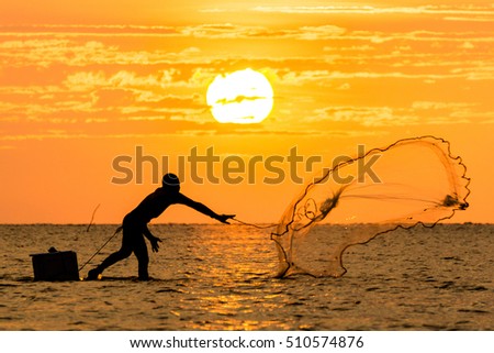A group of people in silhouette spent quality time by casting a fishing net with orange sunset color at background.