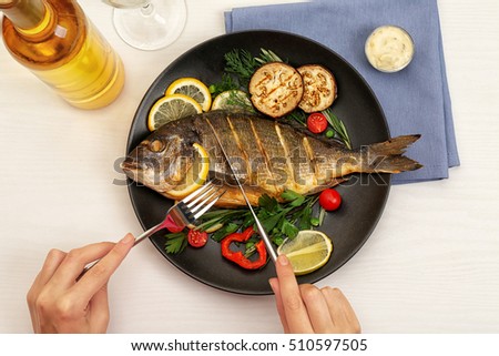 Female hands cutting tasty fish on plate Royalty-Free Stock Photo #510597505