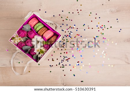 Flowers in a gift box and colorful confetti on a wooden background