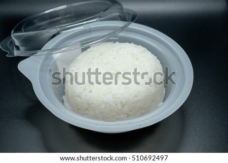 White steamed jasmine rice in plastic cup.ready to warm in the microwave.city life. in black background.