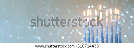 Image of jewish holiday Hanukkah background with menorah (traditional candelabra) and burning candles. Glitter overlay. Wide format