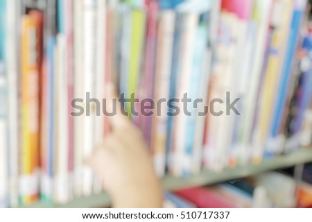 Blur abstract background of books on shelf in school library. Blurry image of school student hand scan books from the shelf. Defocus child pupil picking textbook or fictions to read.