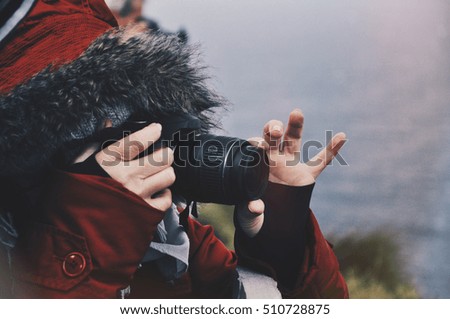 Photography in extreme cold nature conditions, passion and hobby concept. Hooded person wearing winter warm clothes taking picture with reflex camera, 