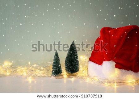 Low key Image of christmas tree with garland warm lights next to santa hat