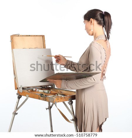 A young woman near easel begins to draw a picture.