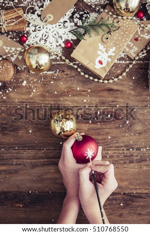 Packaging holiday gifts.Young girl packs a Christmas gift  with Christmas decorations. Toned picture. Top view