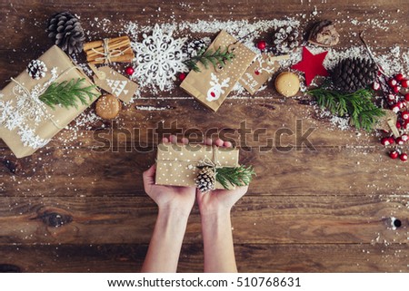 Girl's hands hold Christmas or new year decorated gift box. Toned picture. Top view