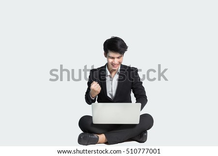 Asian business man working on a laptop and sitting on the floor isolated over white background