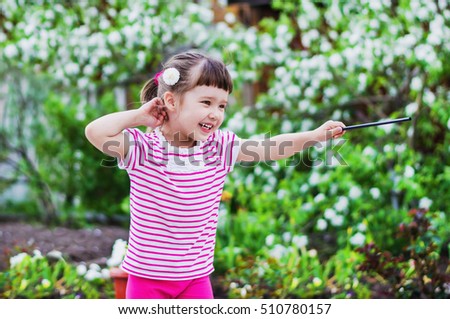 Cheerful little girl is a magician the flowered garden in summer