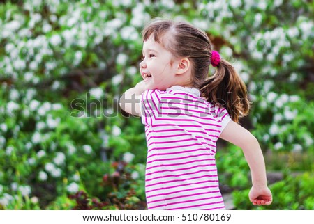 Cheerful little girl on a walk the flowered garden in summer
