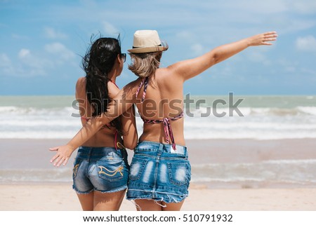 Back view of two women having fun on the beach