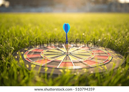 Blue dart arrow hitting on center of dartboard with sunlight - Vintage light leak effect & selective focus