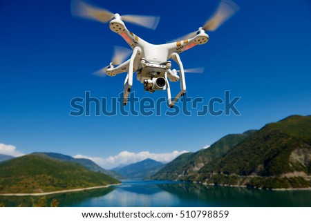uav drone with high resolution digital camera flying in the blue sky over the mountain at lake