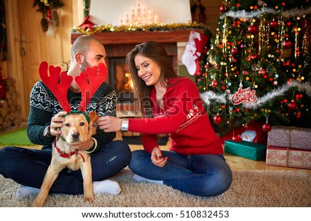 
Young couple making fun with nice dog for Christmas 