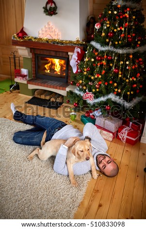 Man enjoy with dog on Christmas eve near fireplace