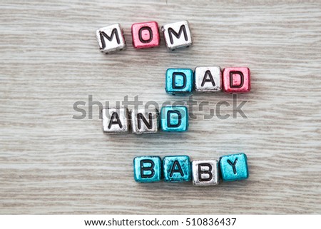 MOM DAD AND BABY cube blocks arranged on gray wooden background