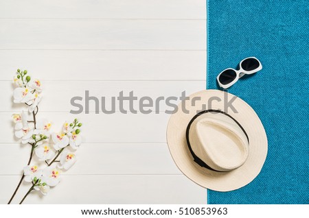 Top view of beach summer accessories with copy space. Lay flat holiday fashion background on white wooden table or floor. Horizontal frame for spa or wellness concept.