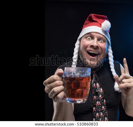 Comic actor man in cap with braids with a glass of beer on a black background, in anticipation of Christmas and New Year 