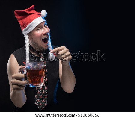 Comic actor man in cap with braids with a glass of beer on a black background, in anticipation of Christmas and New Year