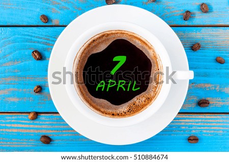 April 7th. Day 7 of month, calendar written on morning coffee cup at blue wooden background. Spring time, Top view