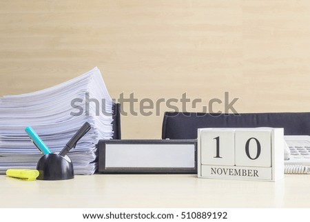 Closeup white wooden calendar with black 10 november word on blurred brown wood desk and wood wall textured background in office room view with copy space , selective focus at the calendar