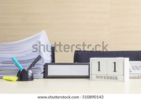 Closeup white wooden calendar with black 11 november word on blurred brown wood desk and wood wall textured background in office room view with copy space , selective focus at the calendar