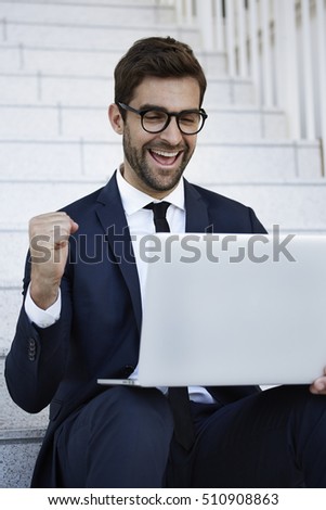 Celebrating businessman using laptop