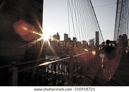 Woman taking a picture to Manhattan views at Brooklyn Bridge. Ray of light. New York City